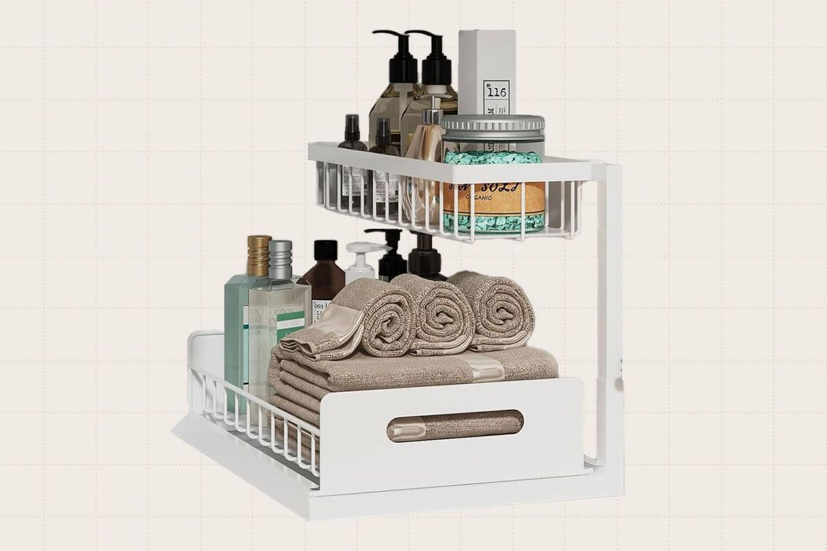 The REALINN Under Sink Organizer against a beige background. The metal organizers come in a pack of two and have slide-out drawers. Pictured here is the white option but it also comes in black and gray.