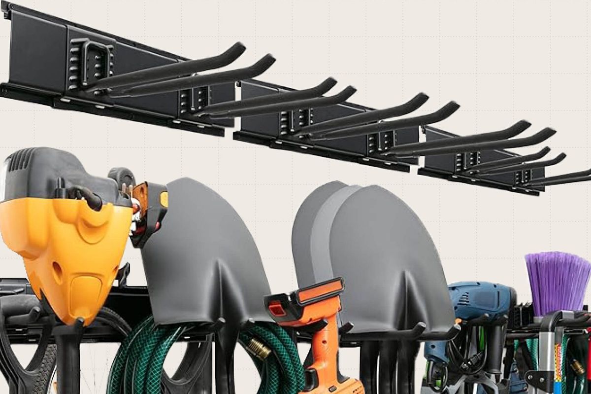 A close-up of the TIDYME Wall Mounted Garden Tool Organizer holding a bunch of different household tools including shovels, hoses, and brooms.