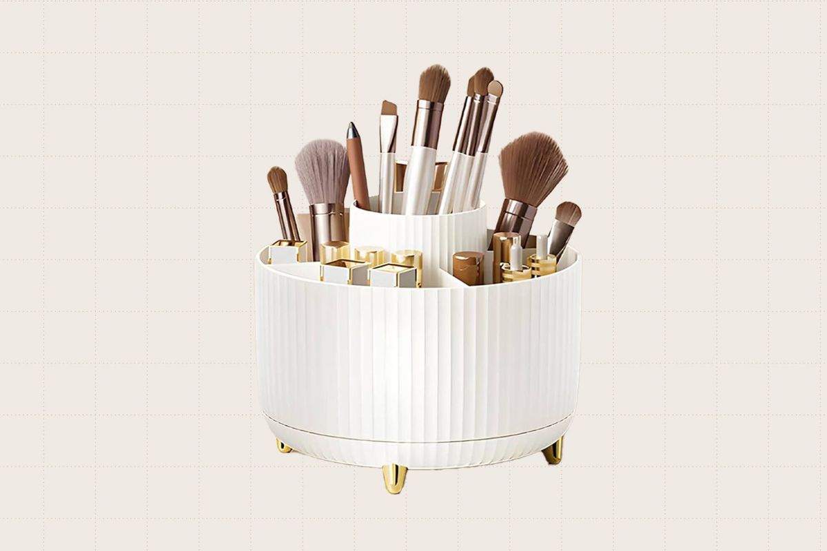 The Diesisa Rotating Makeup Brush Organizer. It's white with a ribbed texture and little gold feet. There are five different compartments for storing brushes.