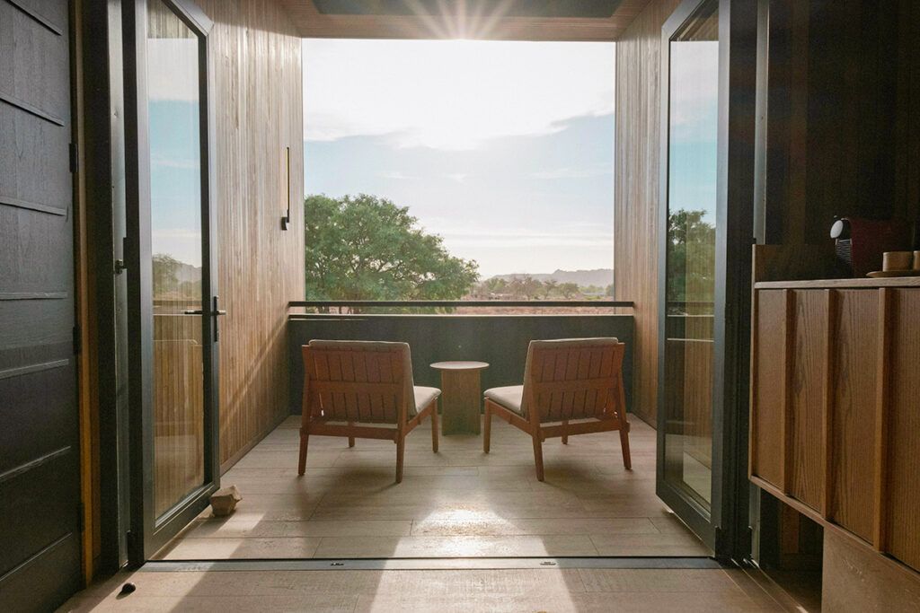 An inset balcony with wooden floors, two lounge chairs, and a drink table.
