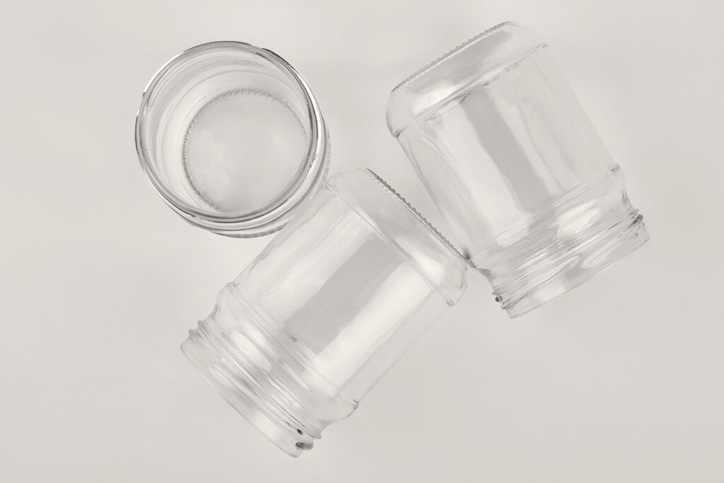 Three clear glass jars with their labels removed on a white surface, shot from above.