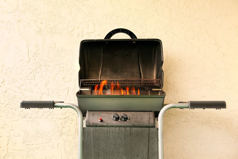 An on-fire grill against a beige stucco wall.