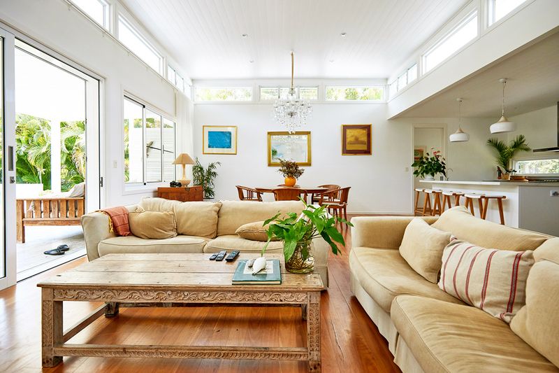 An open-concept kitchen, living, and dining space with white walls, high ceilings, and traditional-style furniture.