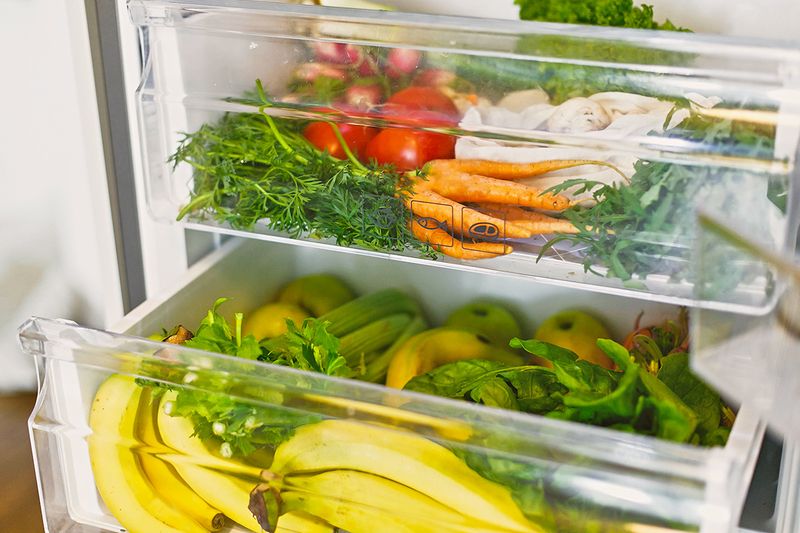 A refrigerator filled with fruits and vegetables. The crisper drawer is open.