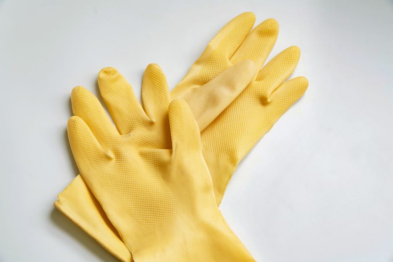 A pair of yellow dishwashing gloves against a white background.