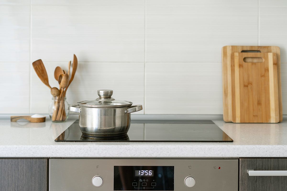A metal pot with a lid on a glass induction cooktop.