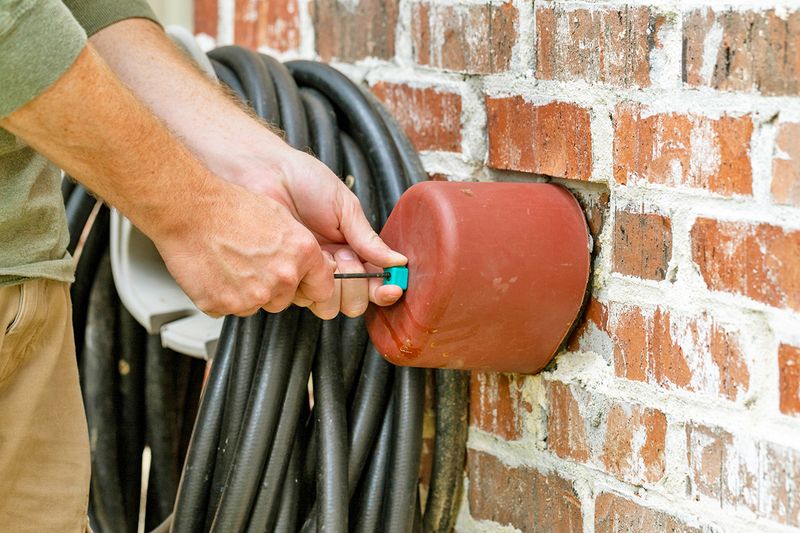 Anonymous person installing an insulated cover over their outdoor faucet.