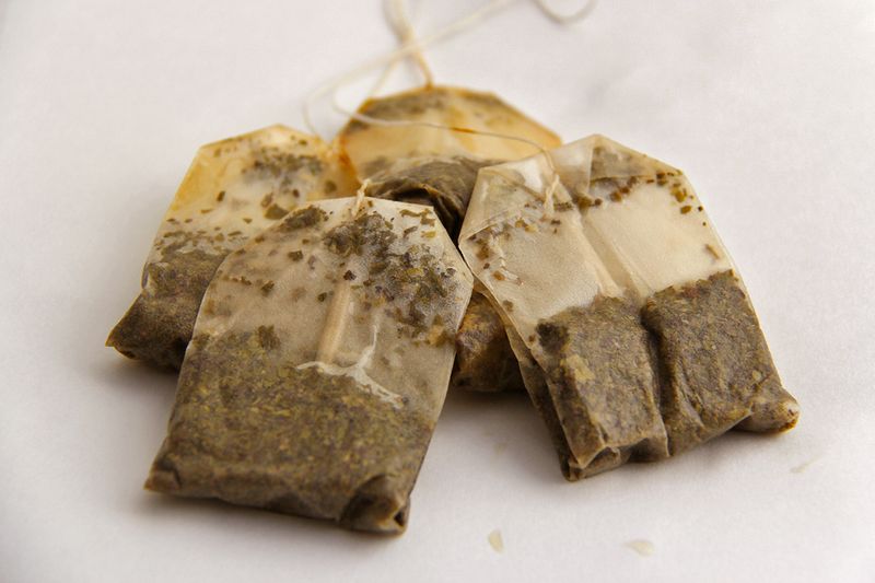 Four used tea bags against a white backdrop.