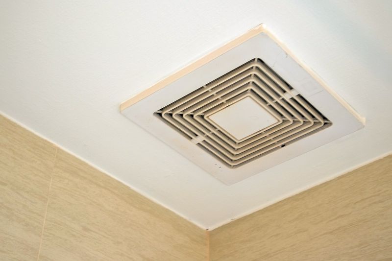 An exhaust fan with a square-shaped cover on a bathroom ceiling.