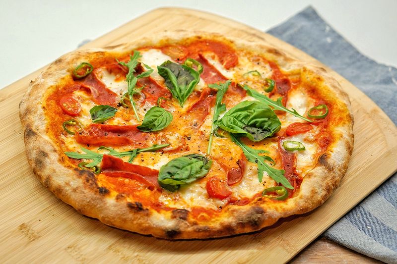 A homemade margherita pizza on a wooden cutting board.