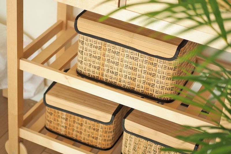 Three woven cork storage boxes on an open, bamboo shelf.