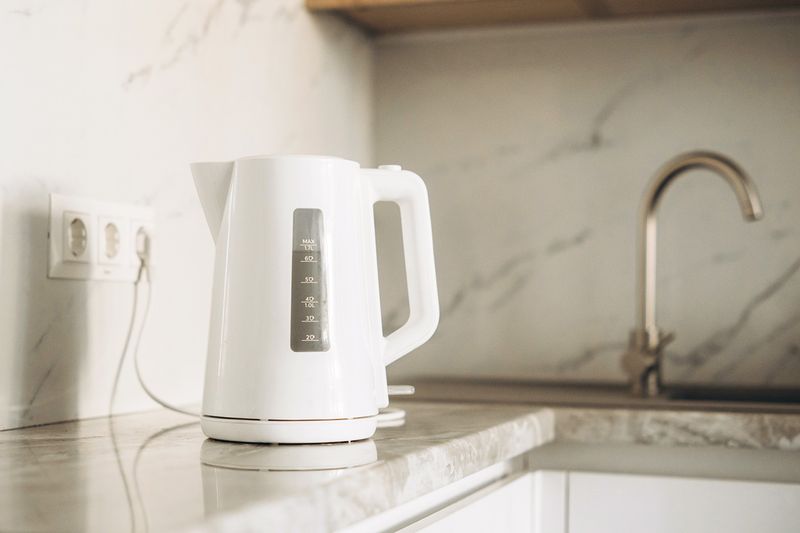 A plugged-in electric kettle on a kitchen countertop.