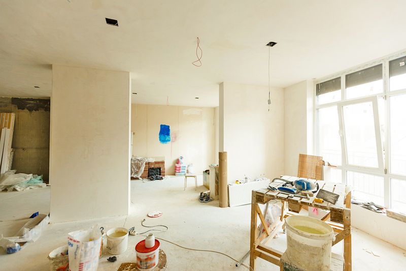 The interior of a house midrenovation with drywall and wiring installed but hardly anything else.