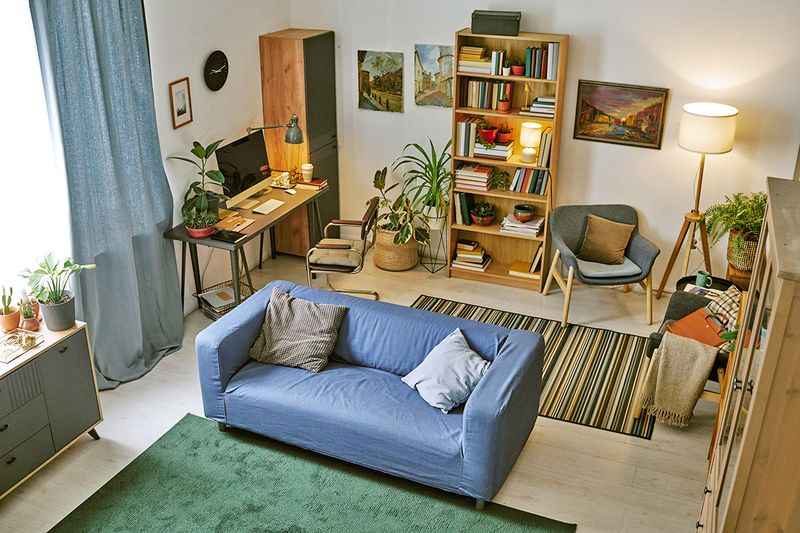 An overhead shot of a living room with a sofa, a workspace, and a reading corner.