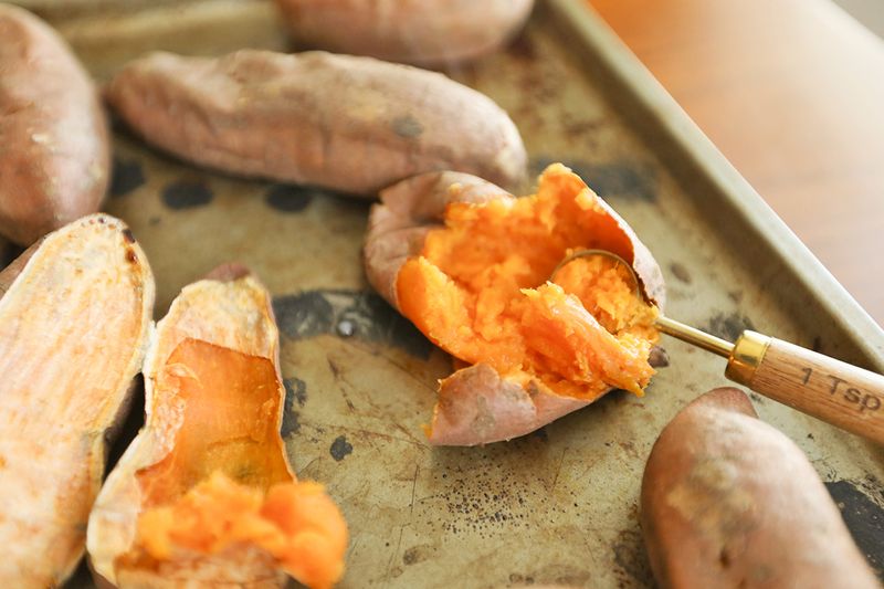 Cooked, smashed sweet potatoes on a baking sheet.