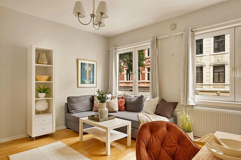 An apartment with a small sectional pushed up against a wall and a small floating area rug.