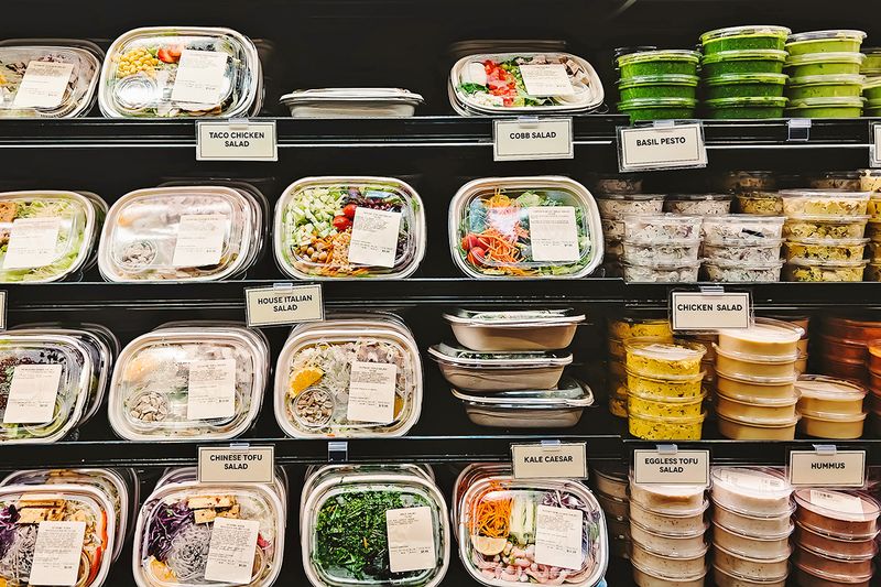 Prepackaged salads on refrigerated shelves at a grocery store.