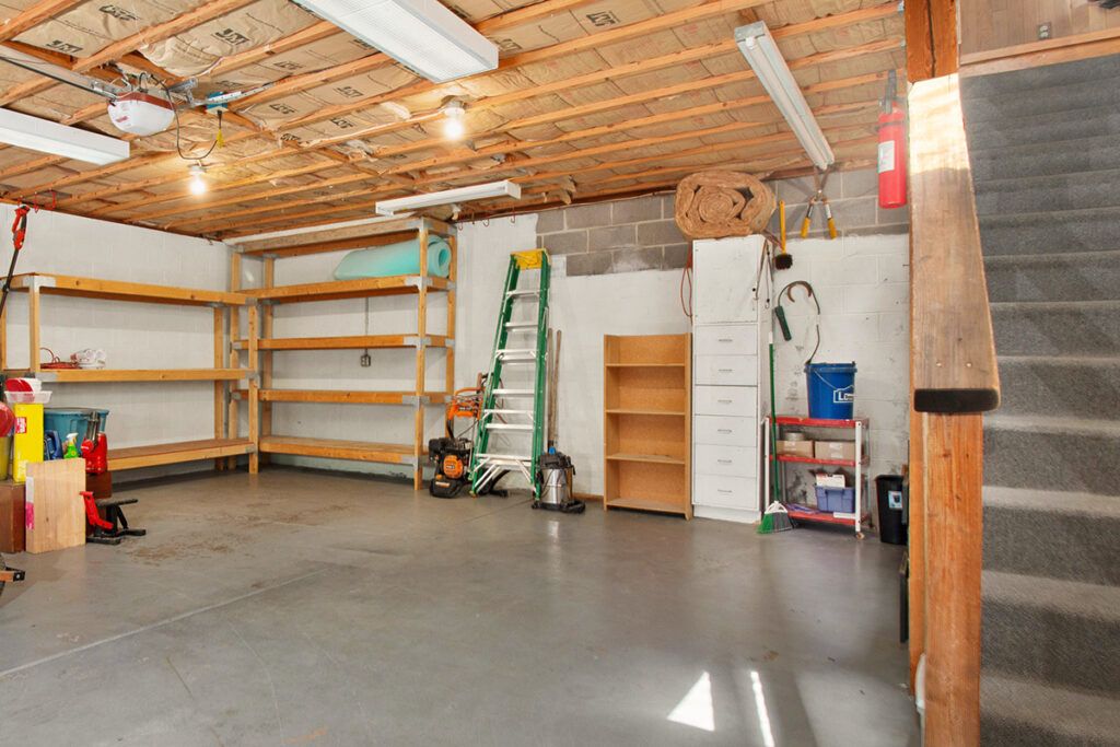 An unfinished but clean basement with a concrete floor and shelves against the walls.