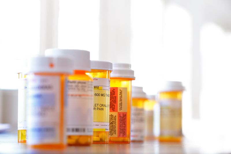 Bottles of medication (some in focus, some out of focus) lined up on a countertop.