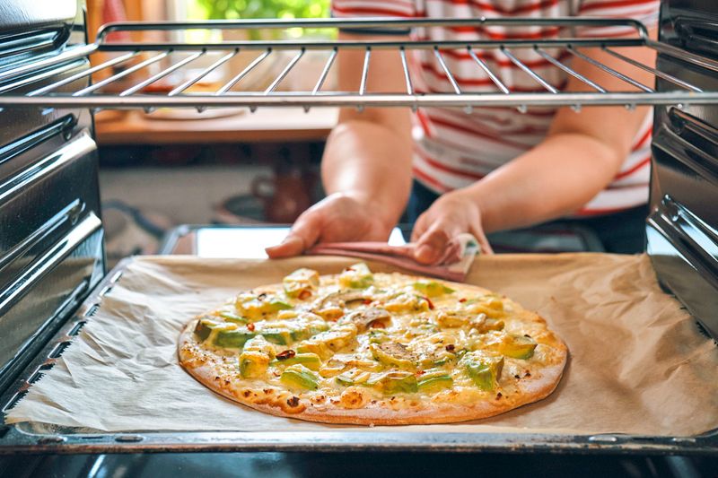 A pizza on a sheet pan lined with parchment paper, placed on the lowest rack.