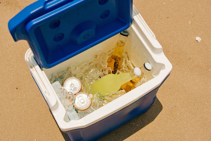 An open portable cooler with ice and drinks inside of it.
