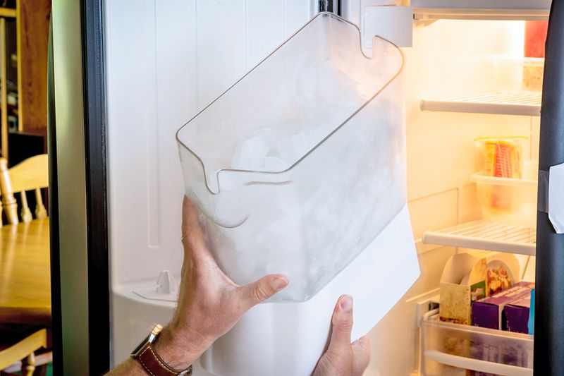 Anonymous person replacing the refrigerator door ice receptacle.