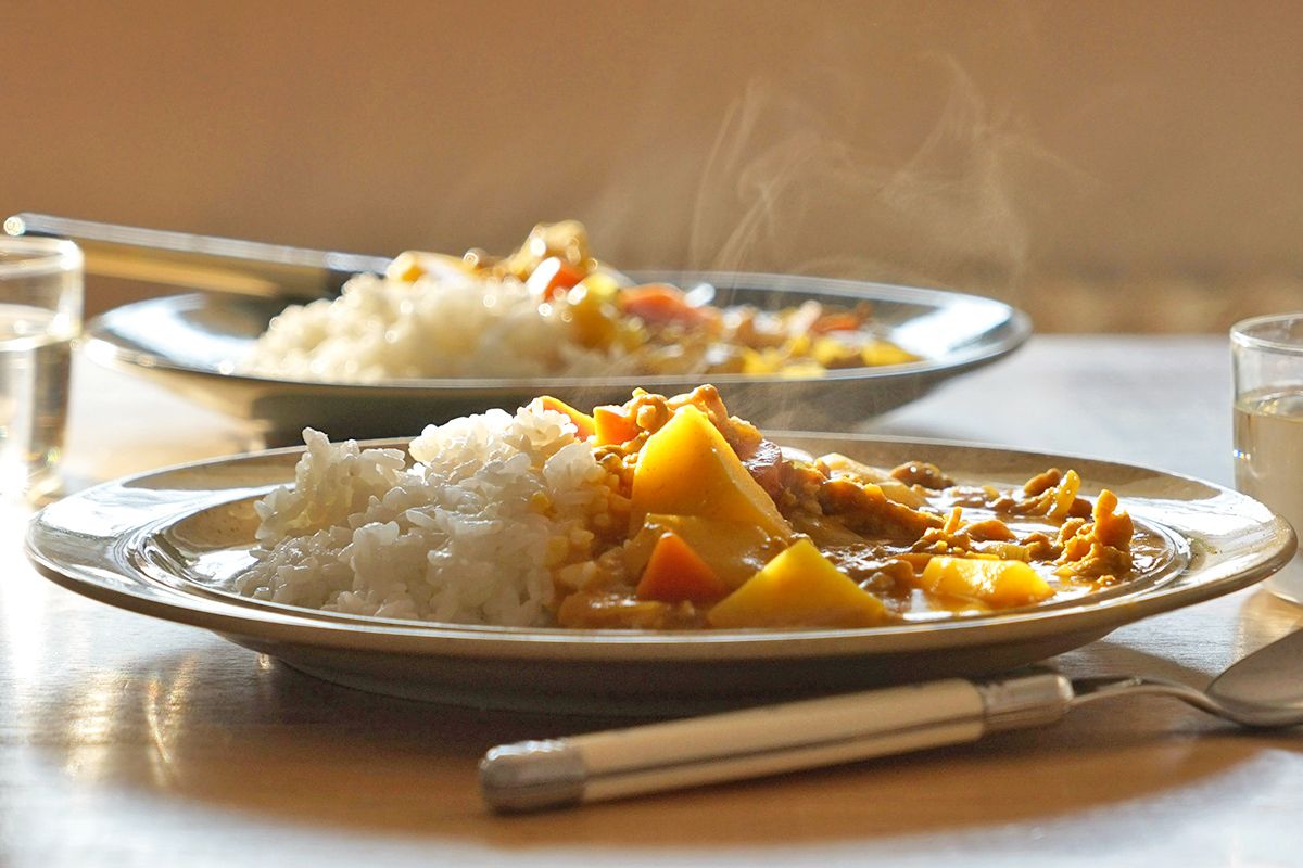 Two steaming plates of a vegetable curry and rice.