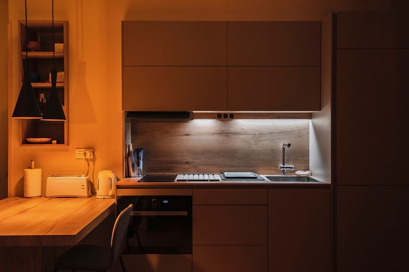A clean, apartment-sized kitchen at night with a few lights on.