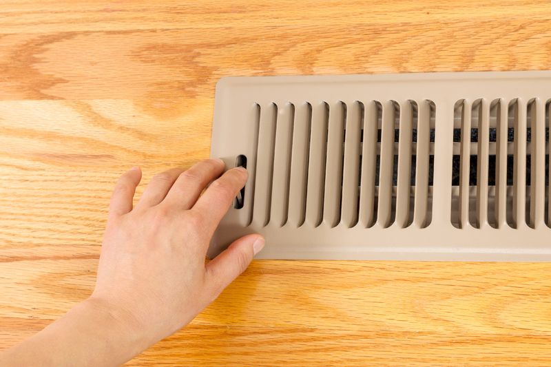 Anonymous person closing an air vent in a wood floor.