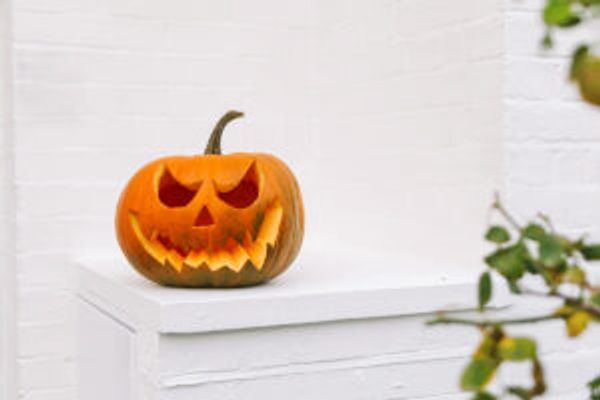 Carved Jack-o-lantern with scary smile against white brick house