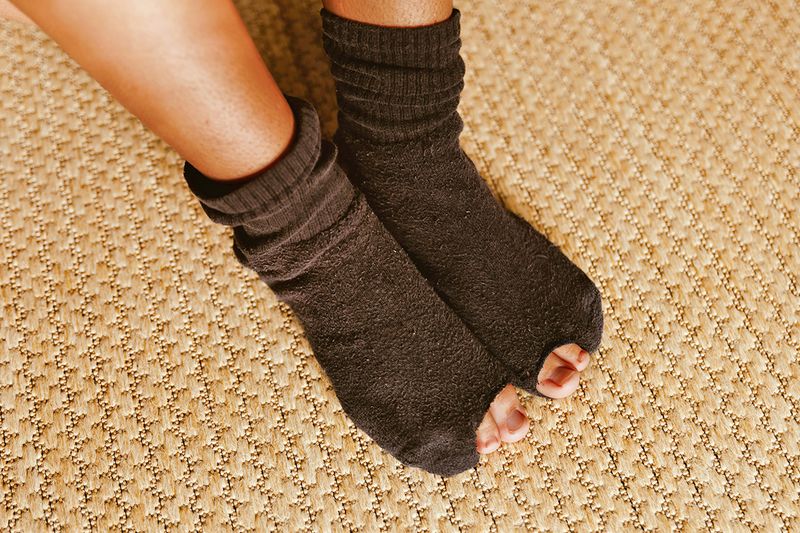 Woman's feet wearing socks with holes in the big toes